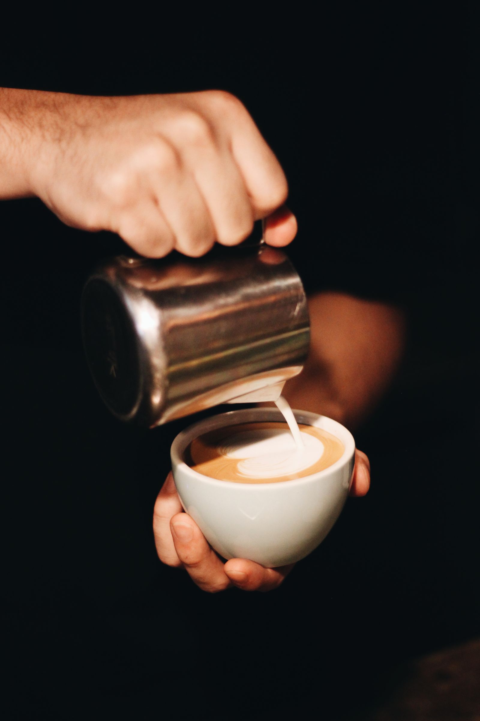 Barista gießt Milch für Latte Art